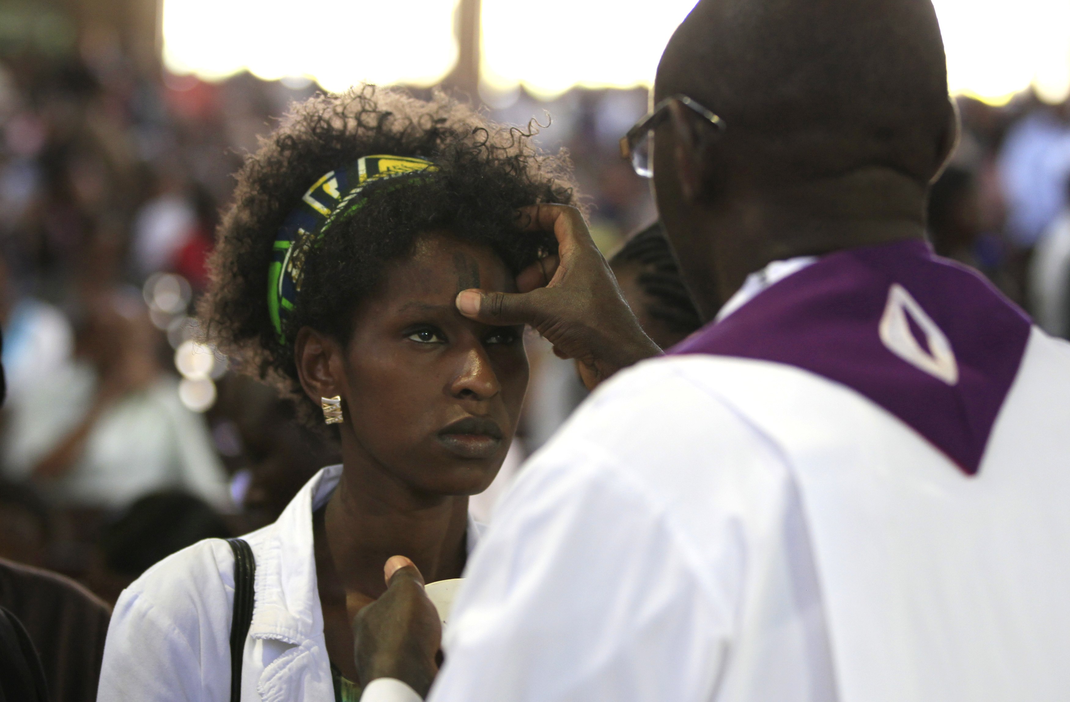 A Roman Catholic priest use ash to mark a cross on the forehead of a faithful during the Ash Wednesday mass at the holy Family minor basilica parish in Kenya's capital Nairobi, February 13, 2013. Catholics round the world celebrated Ash Wednesday, which serves as a reminder that "as a man is dust, so unto dust he shall return" and marks the beginning of the season of Lent. REUTERS/Thomas Mukoya (KENYA - Tags: SOCIETY RELIGION ANNIVERSARY)