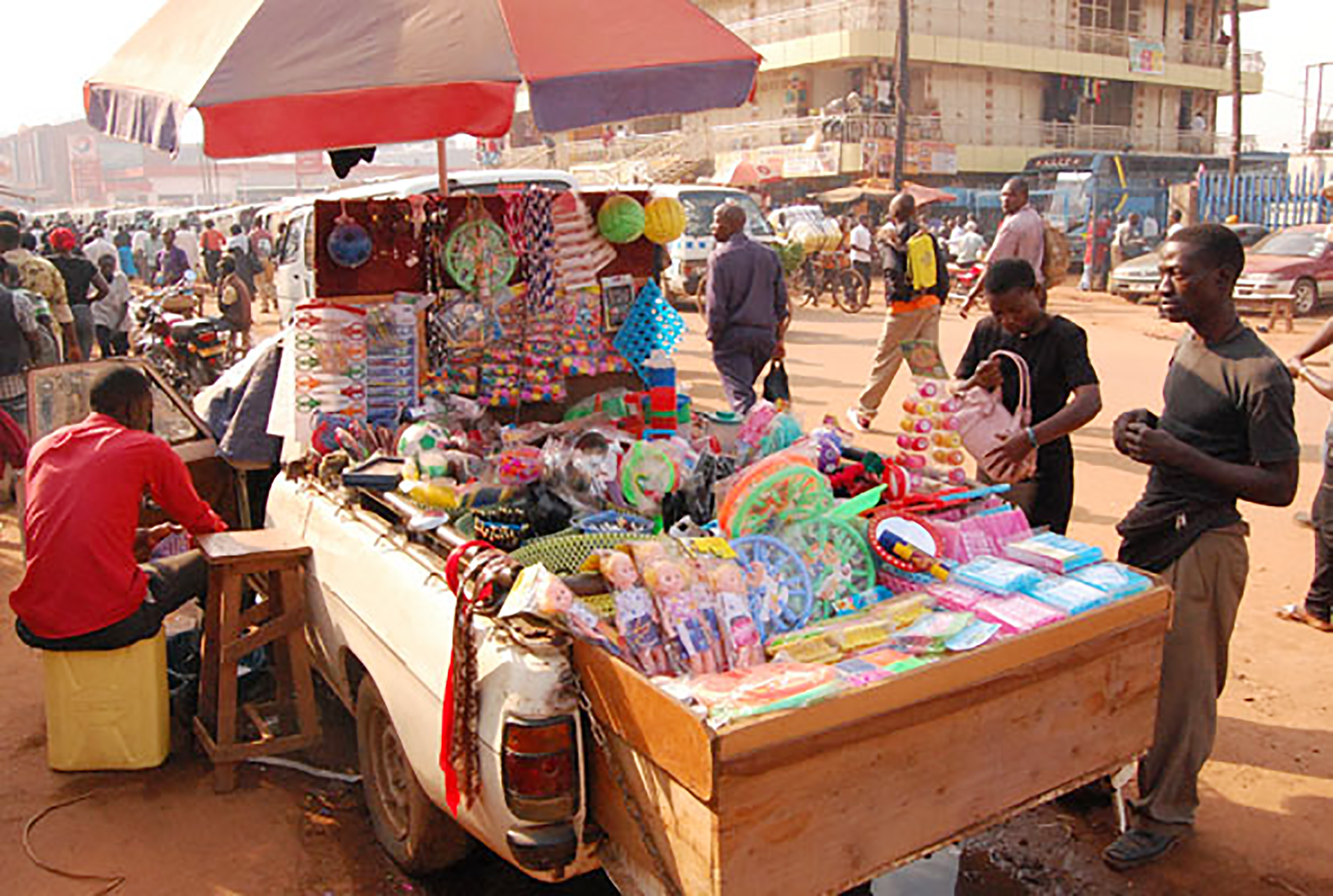 A man uses a wooden bed as a platform on a pick truck to display merchandize near the new taxi park in Kampala on Friday. The multi-purpose pick up serves as a shop, means of transport as well as a store. Kampala Capital City Authority has vowed to chase away vendors from the city streets but there is now a new trend of vendors selling  merchandize in vehicles. PHOTO BY STEPHEN OTAGE