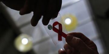 FILE PHOTO: A nurse (L) hands out a red ribbon to a woman, to mark World Aids Day, at the entrance of Emilio Ribas Hospital, in Sao Paulo December 1, 2014. REUTERS/Nacho Doce