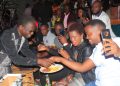 Moses Matovu serves cake to his fans. Photo by Joseph Kasigwa.